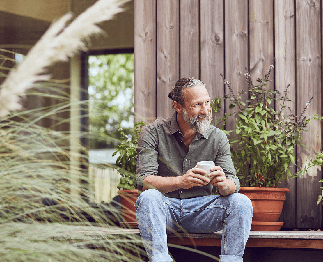 Photo d'un homme assis devant une maison en bois